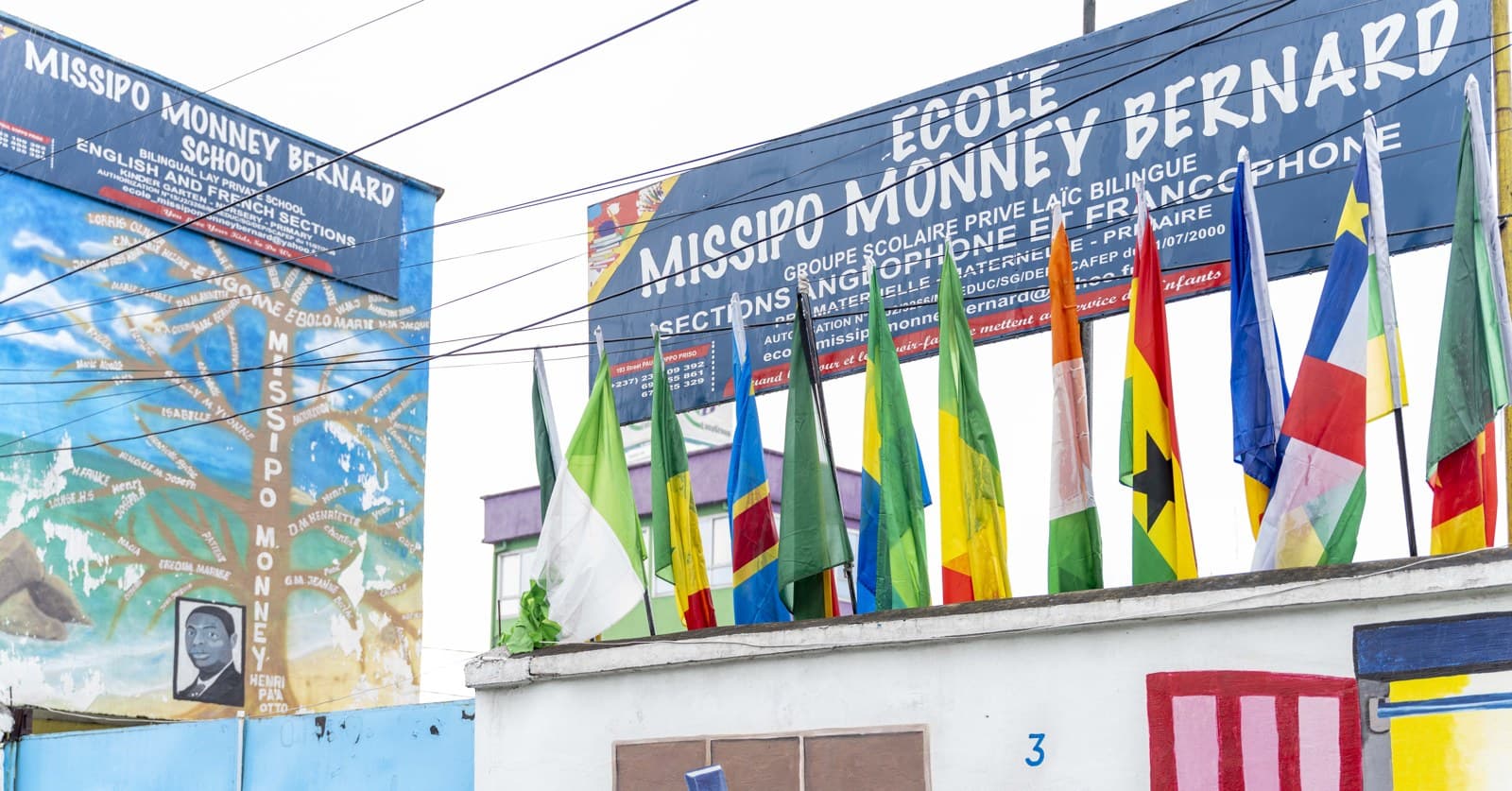 L'enseigne de l'école, entourée des drapeaux des sections bilingues
